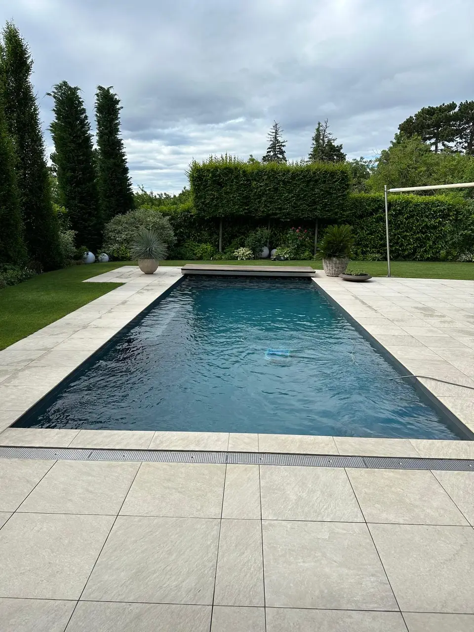 Rechteckpool mit dunkler Auskleidung und Natursteinterrasse